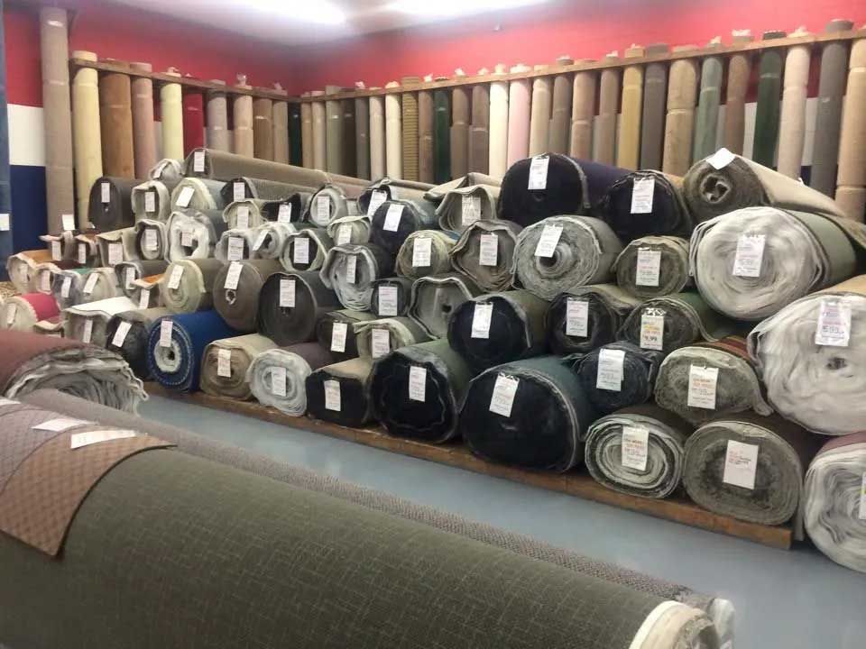 A carpet store with many rolls of carpet in various colors stacked and displayed.