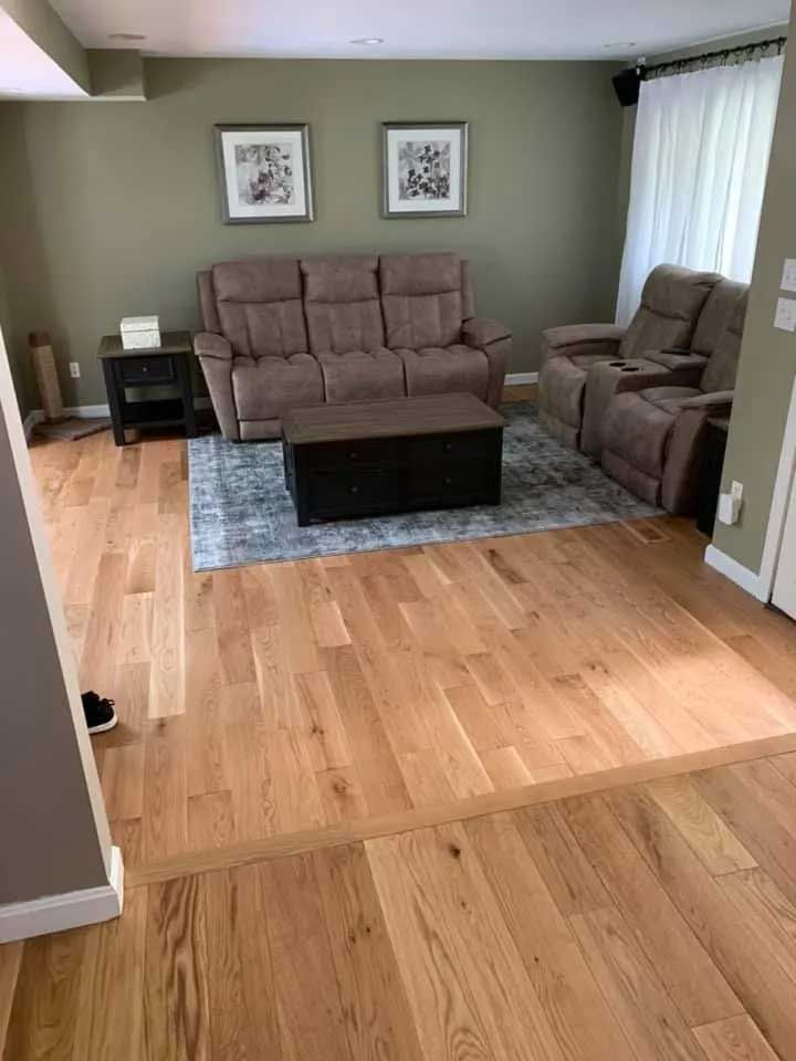 Living room with hardwood floors, beige recliner furniture, olive green walls, and a black trunk coffee table.
