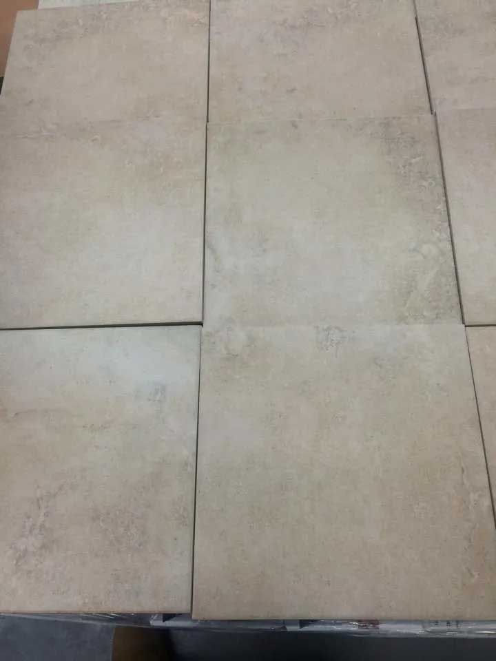 Beige square tiles arranged in a grid, displaying a muted, textured surface.