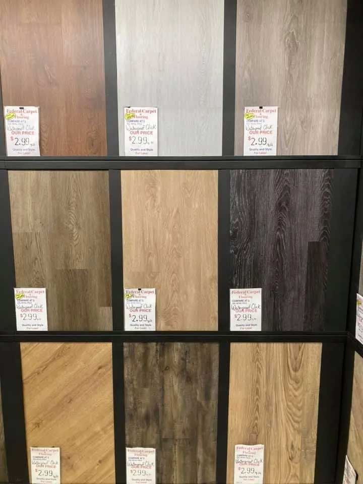 Flooring samples in various wood grain colors displayed on a black wall at a store.