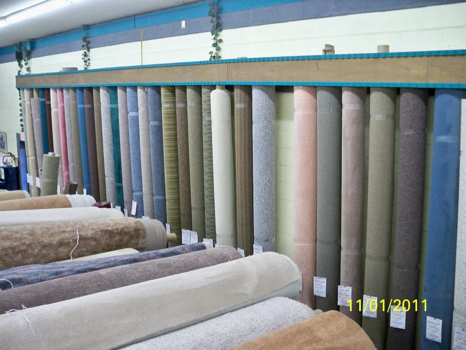 Rows of carpet rolls in various colors at a flooring store.