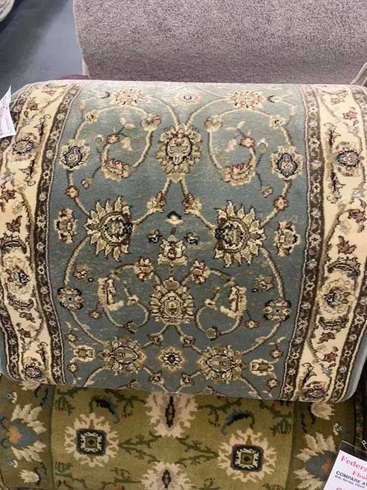 Rolled-up rug with floral design in blue, cream, and brown.