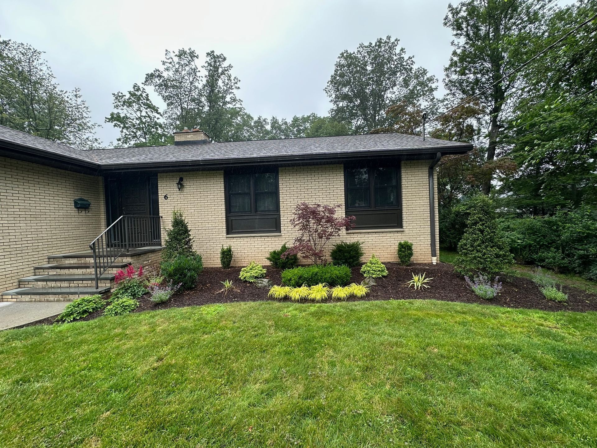 Beige brick house with manicured landscaping and a grassy lawn.