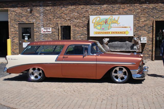 A brown and white car is parked in front of a building that says custom insurance