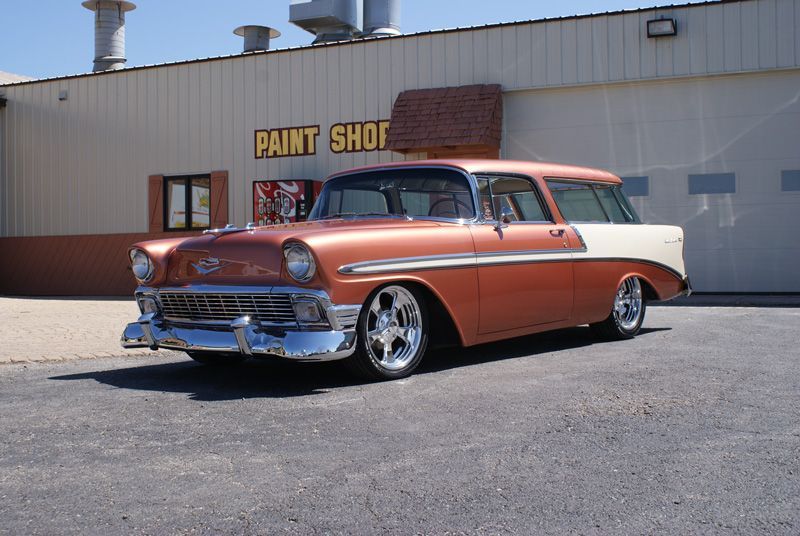 A red and white car is parked in front of a paint shop