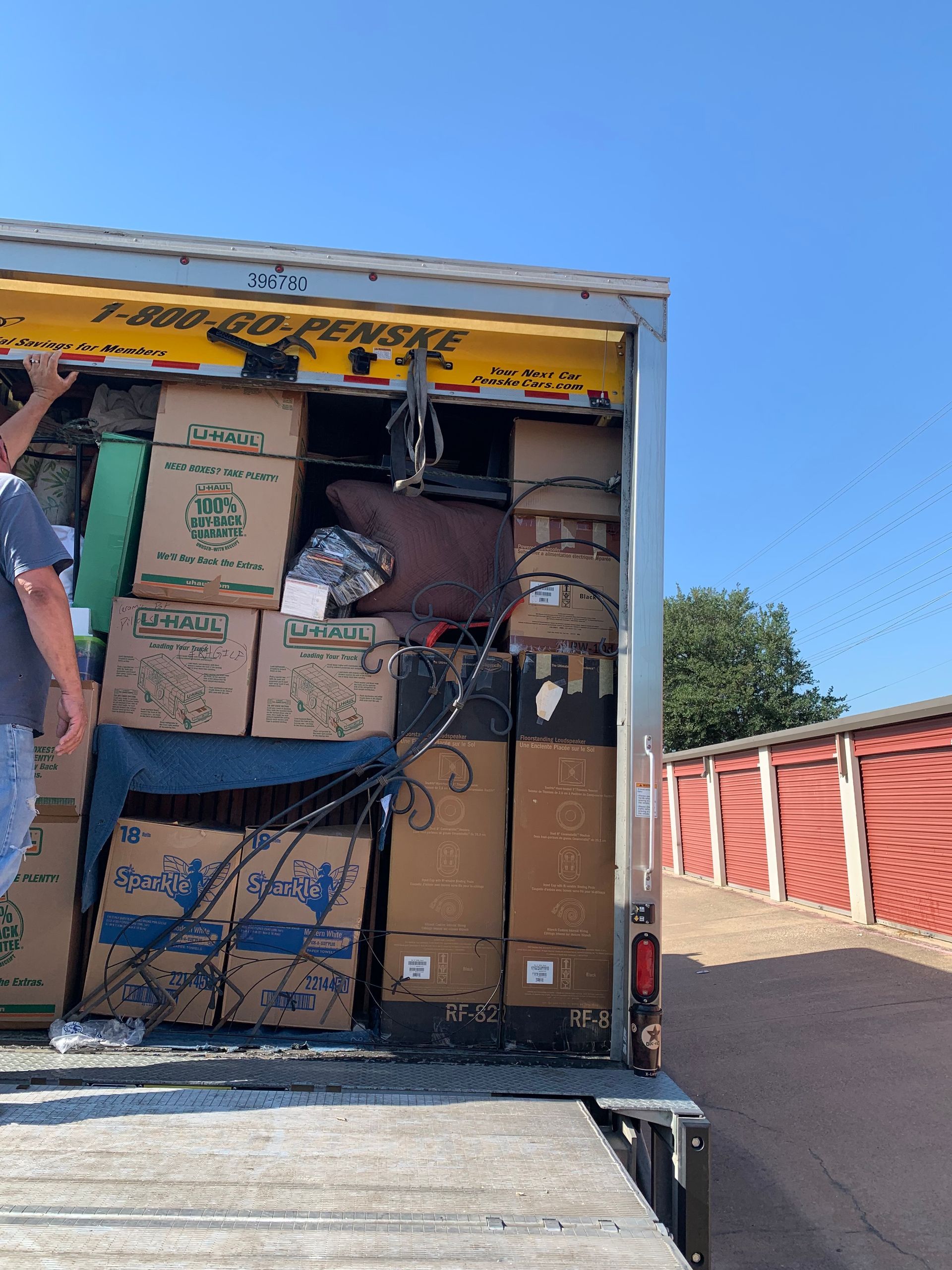 A man is standing in front of a moving truck filled with boxes.