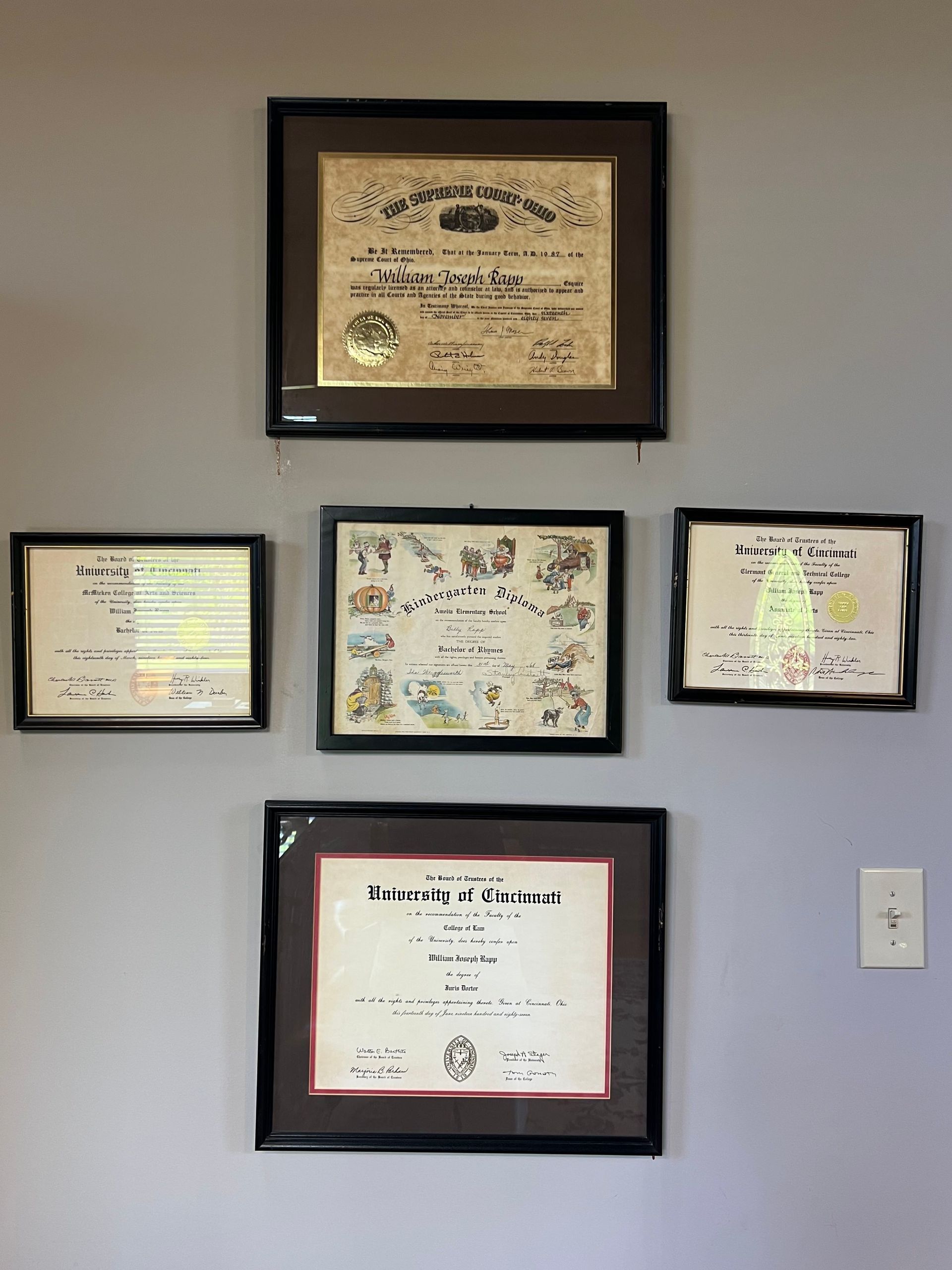 Four framed certificates and awards arranged on a light-colored wall.