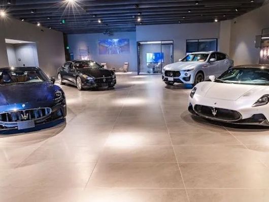 Luxury cars displayed in a bright showroom with tiled floors and spotlights