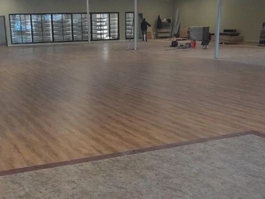 Empty indoor room with wood flooring, large windows, and a concrete column.