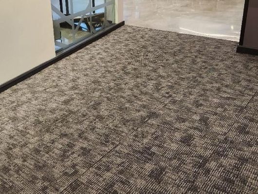 Carpeted hallway with a glass railing and beige tile floor in the distance
