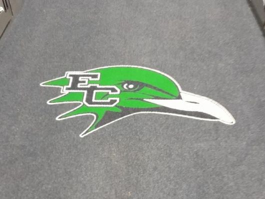 Green bird logo with white beak and EC letters on gray carpet flooring