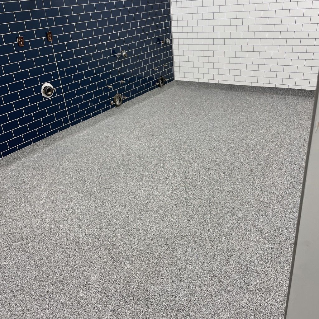 A room with a gray carpet and a brick wall.