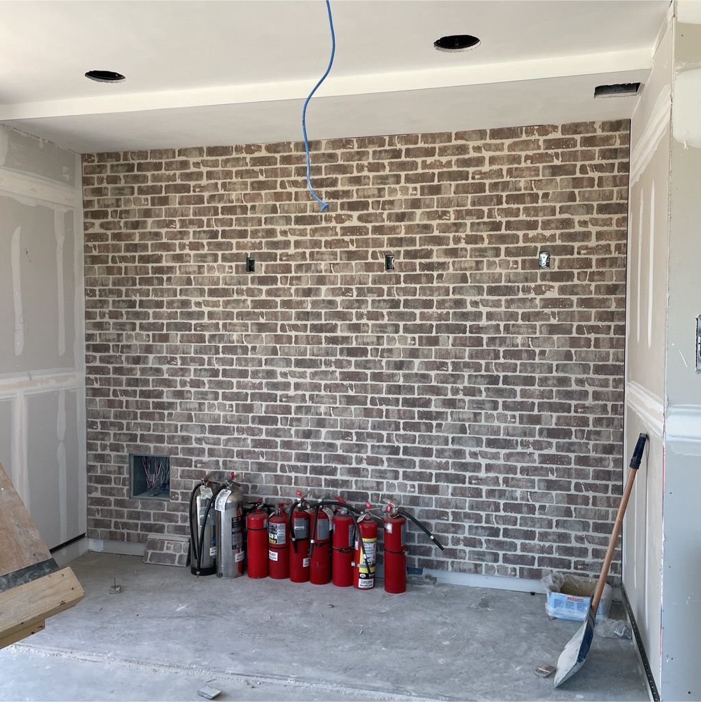 A room with a brick wall and fire extinguishers on the floor.