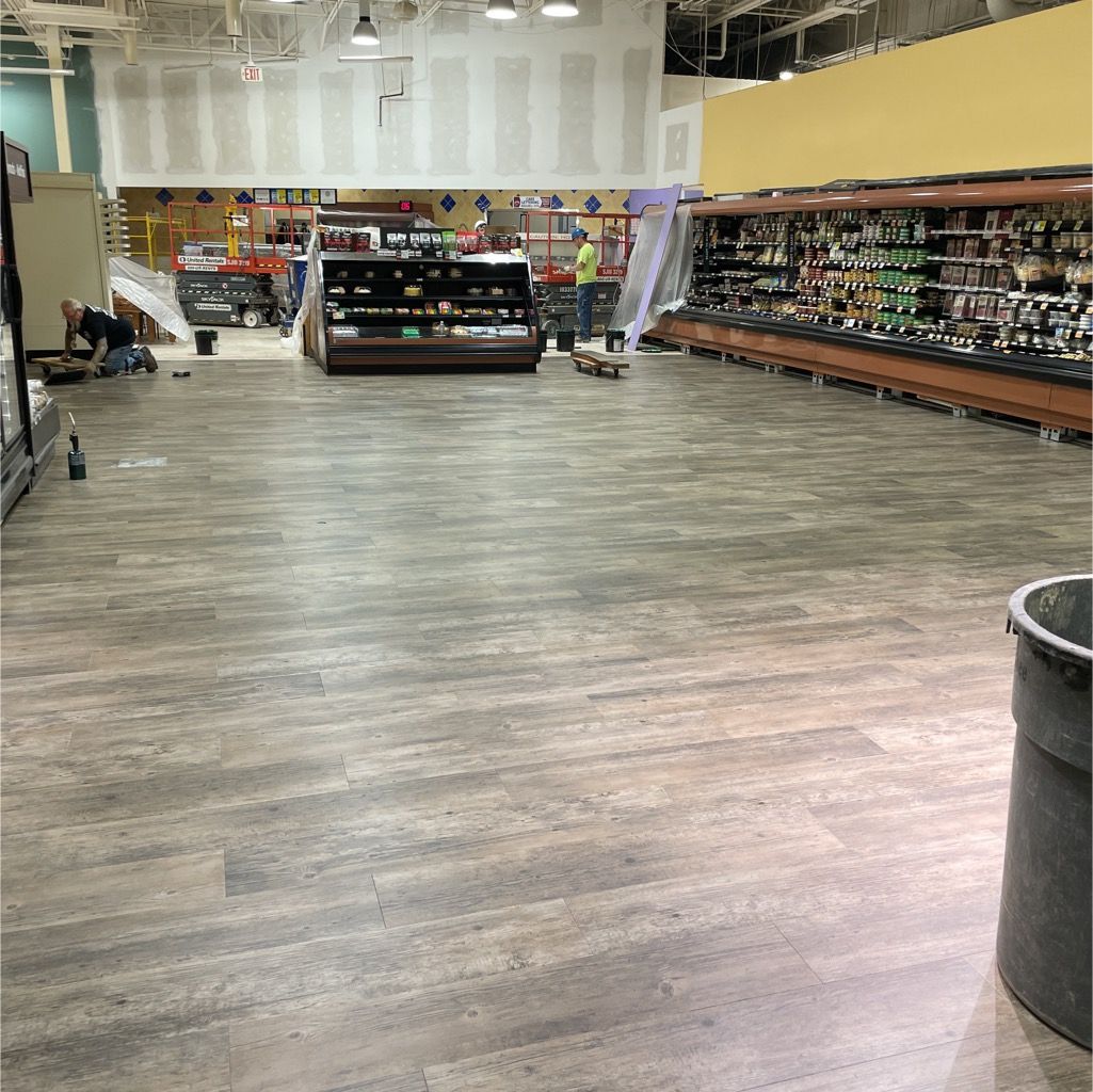 A large room with a wooden floor and a trash can in the middle.