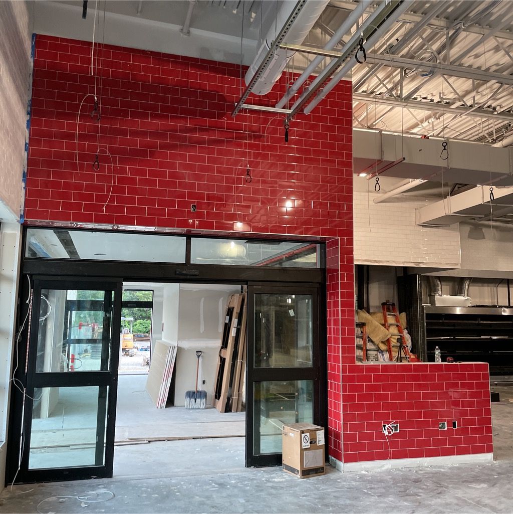 Abuilding under construction with a red brick wall.