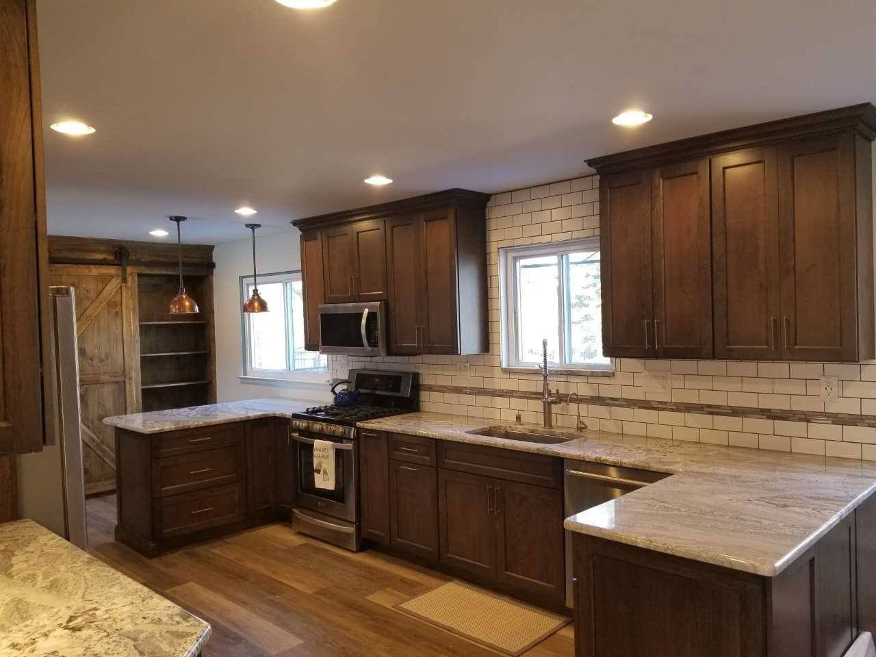 A kitchen with wooden cabinets , granite counter tops , stainless steel appliances and a window.