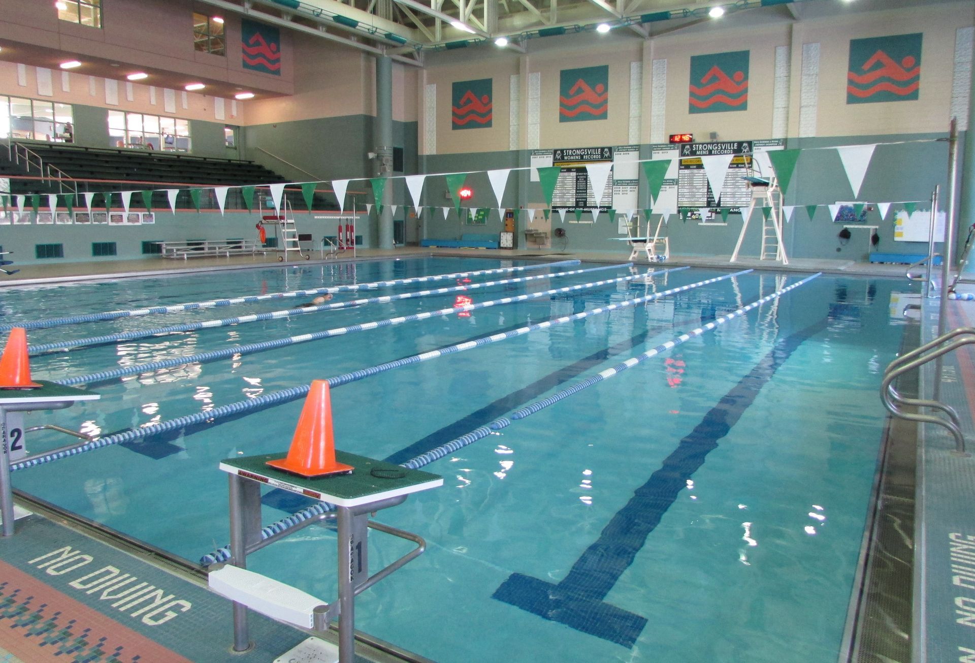 Indoor swimming pool with lanes marked, flags, and diving boards.