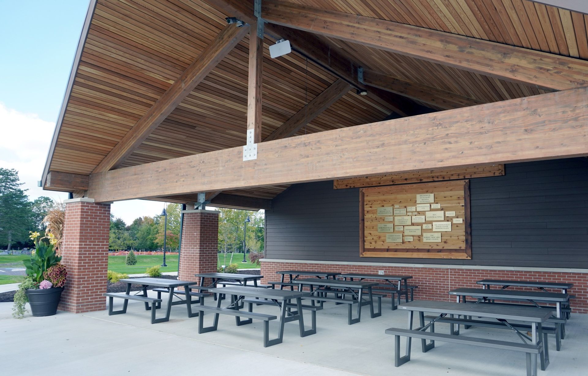 Wooden pavilion with picnic tables; under a wooden ceiling.