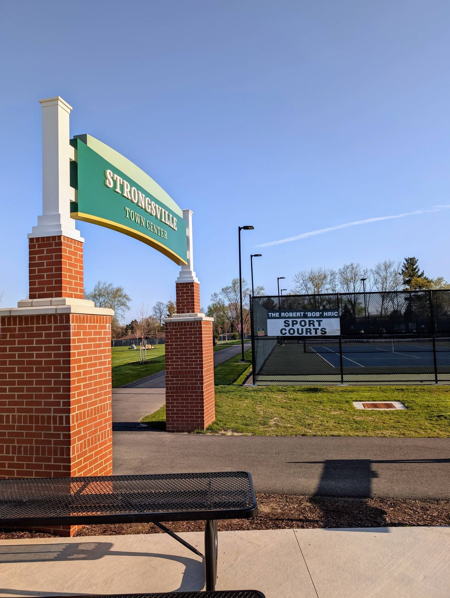 Strongsville Town Center entrance sign with brick pillars and a path leading to a building, under a cloudy sky.