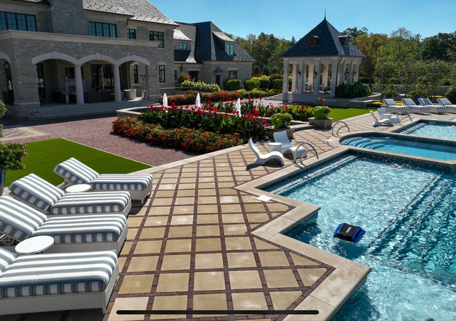 Luxury backyard with pool, patio, gazebo, and large house on a sunny day.