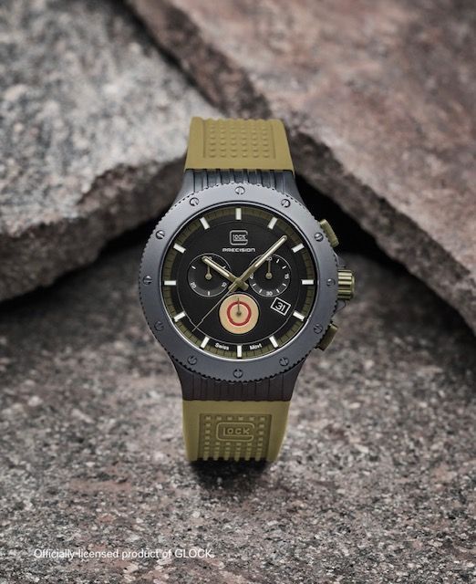 Black and olive green chronograph wristwatch on a stone surface.