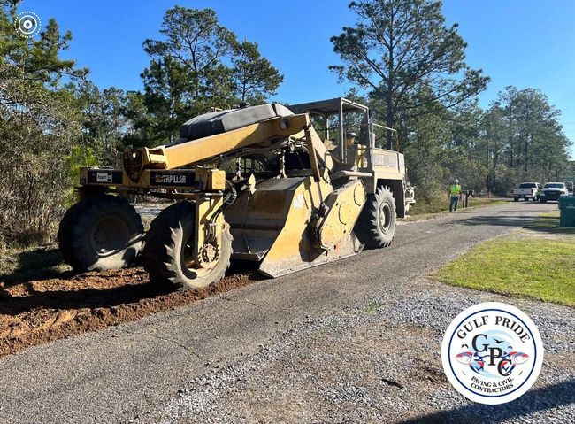 A bulldozer is sitting on the side of a gravel road.