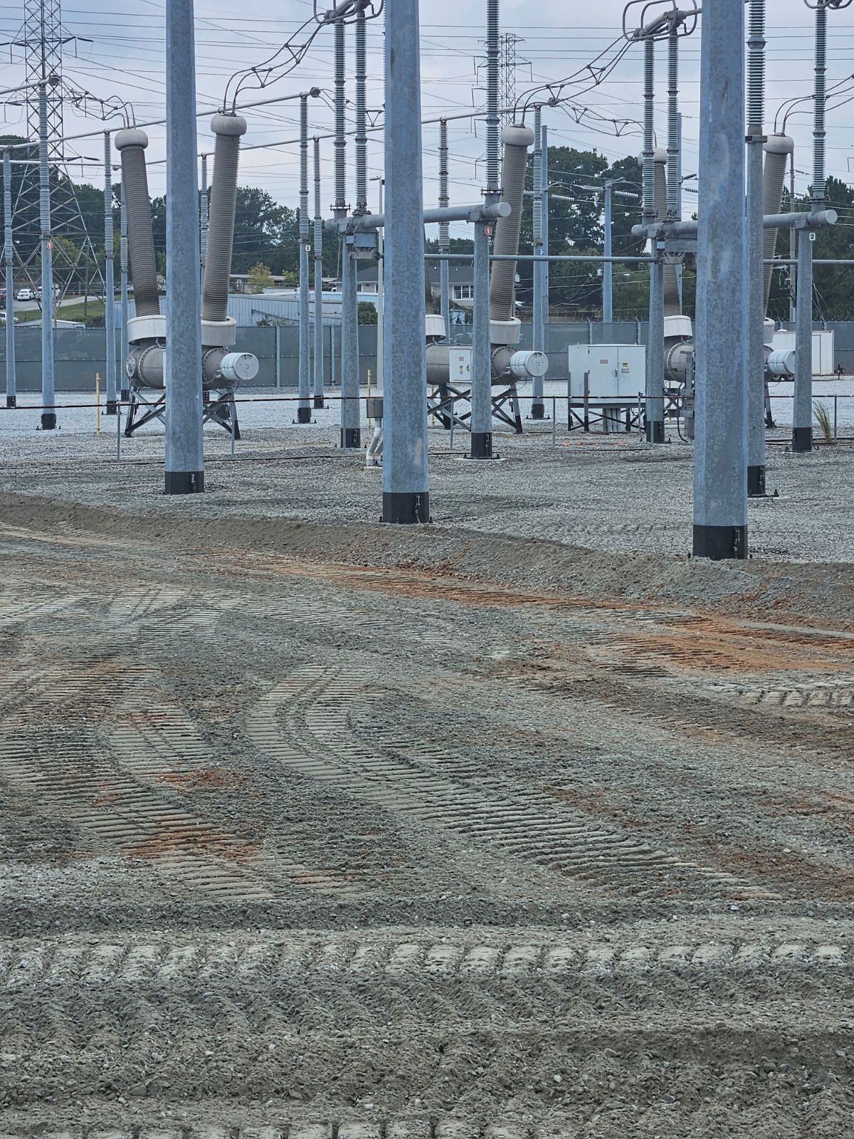 A row of electrical poles are lined up in a field.