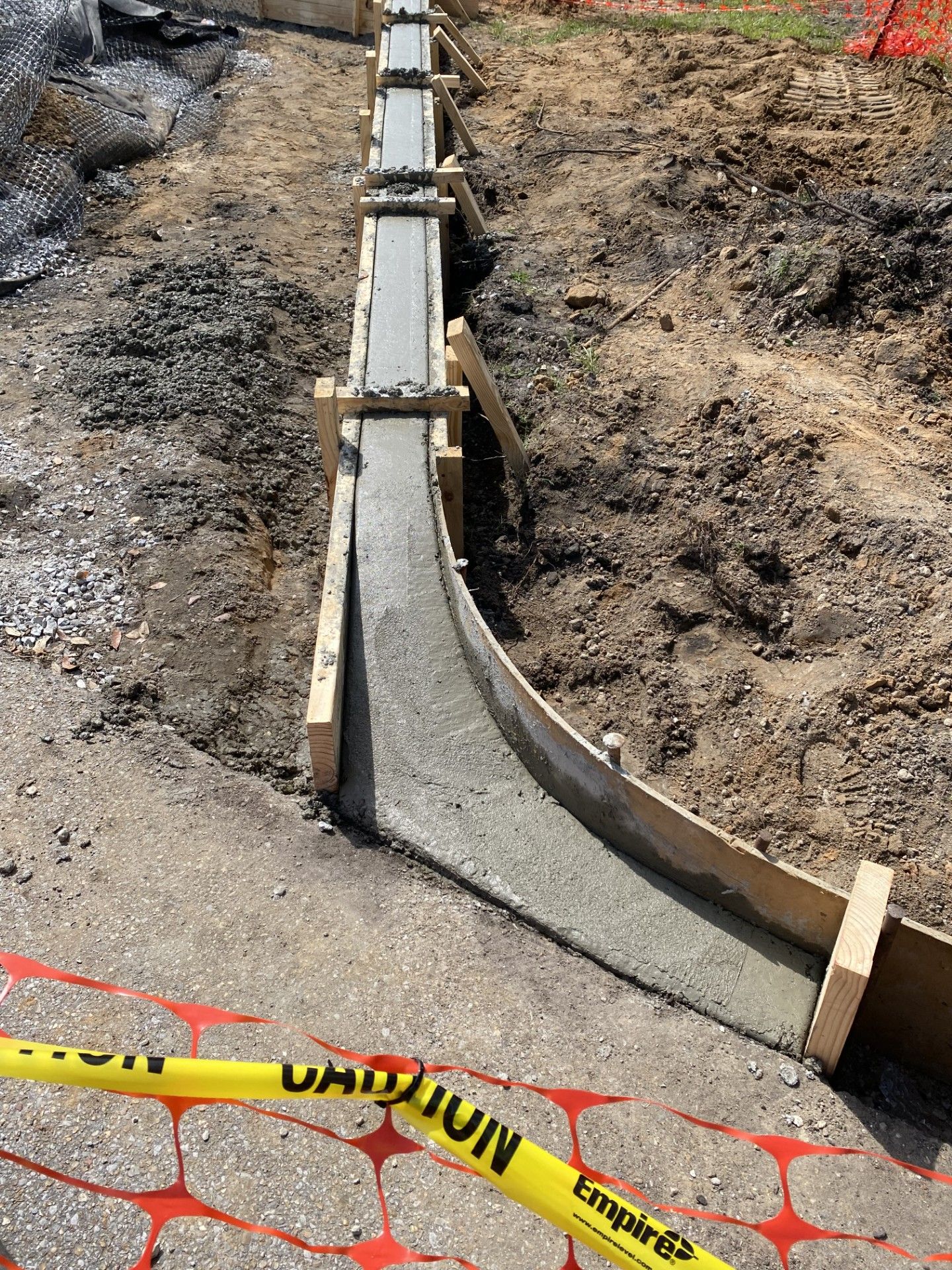 A concrete curb is being built on the side of a road.