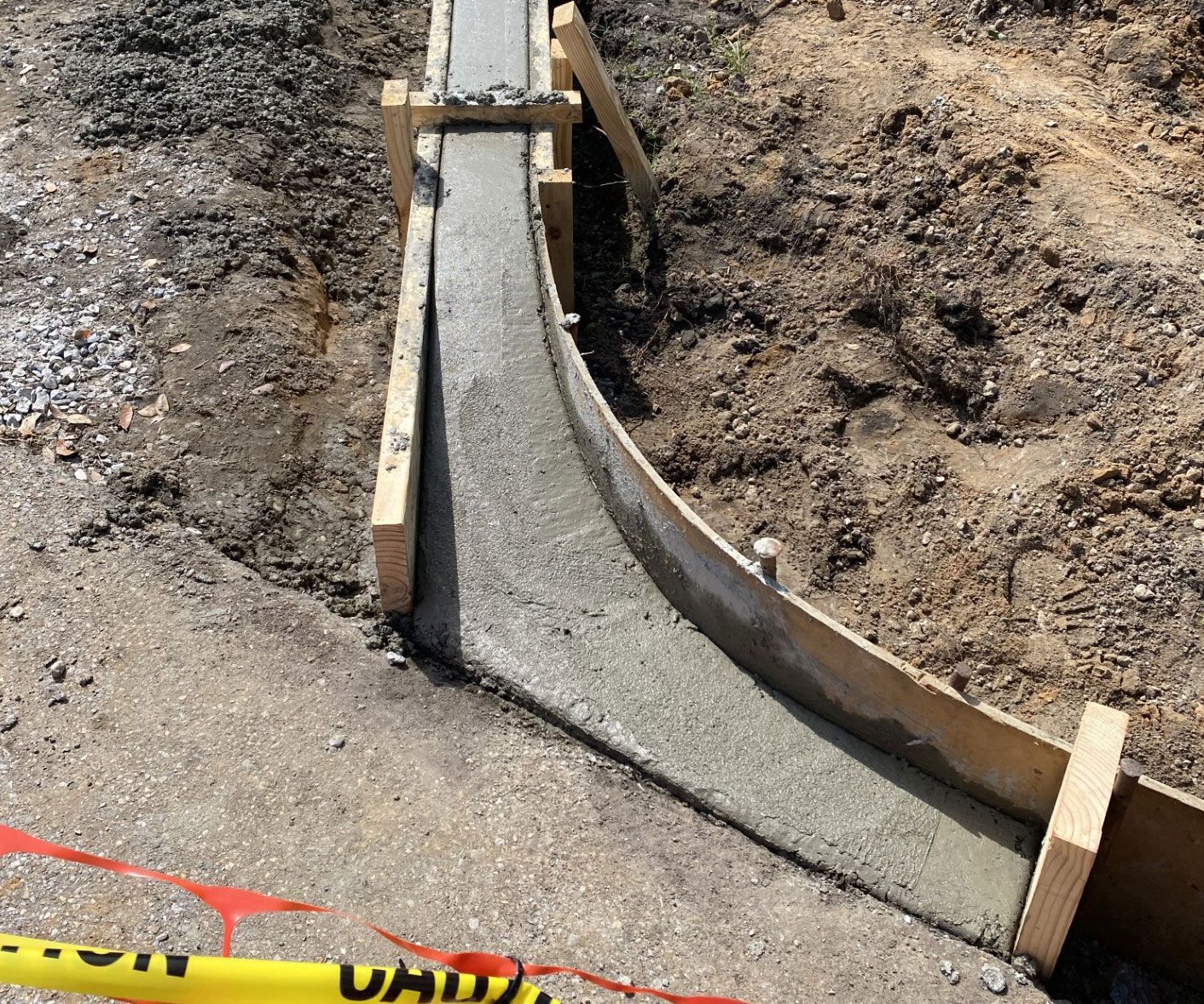 A concrete curb is being built on the side of a road.