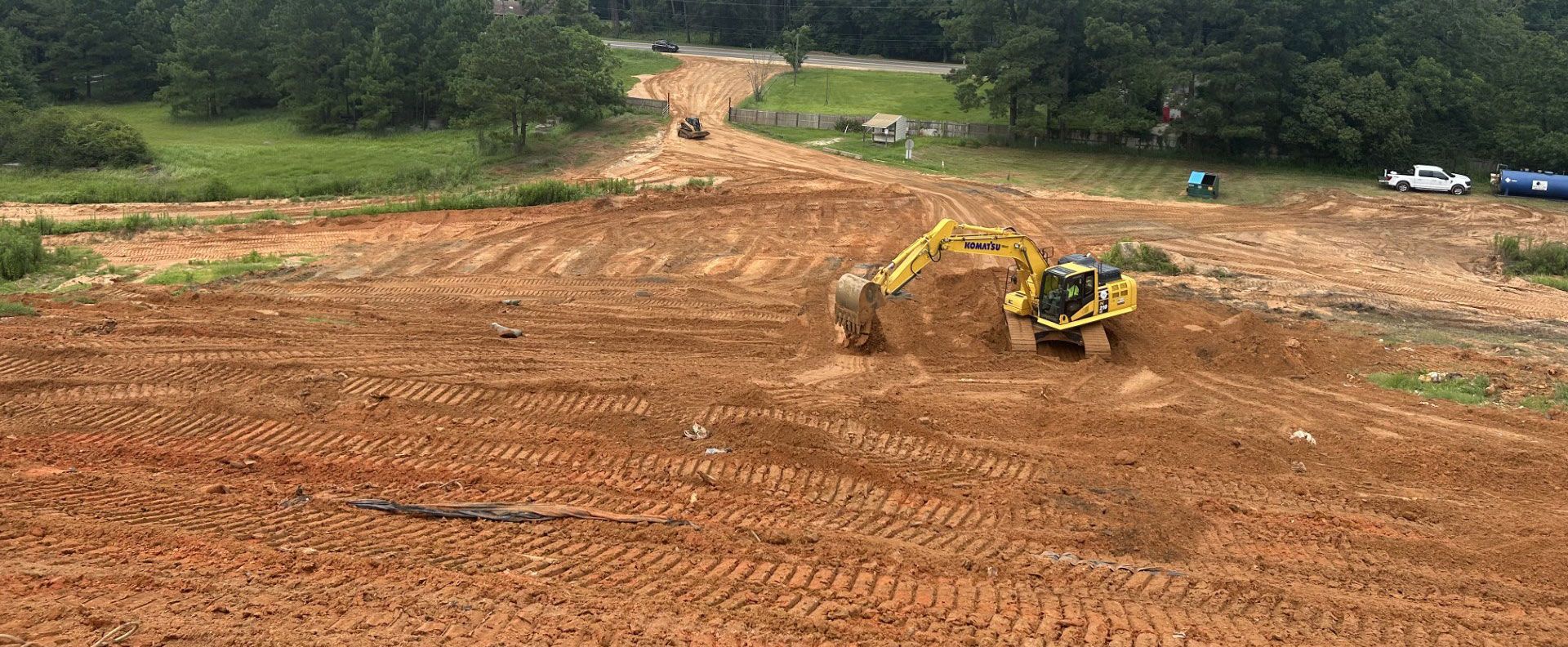 A yellow excavator is working on a dirt field.