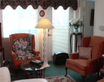 A living room with orange chairs and a lamp