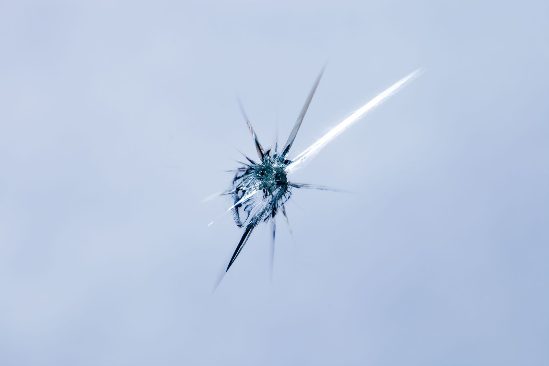 Cracked glass with a starburst pattern, against a light blue background.