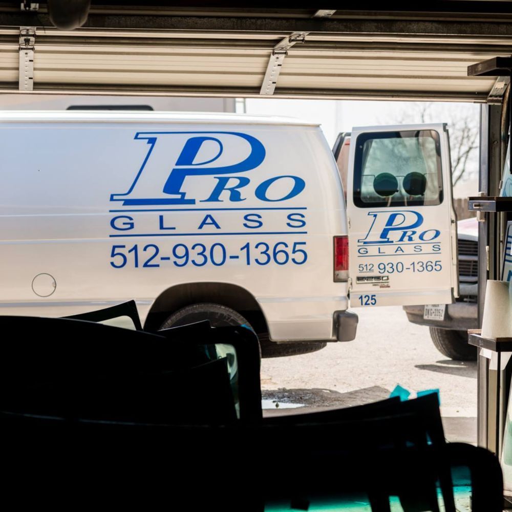 White Pro Glass van with logo and phone number; parked inside a garage.