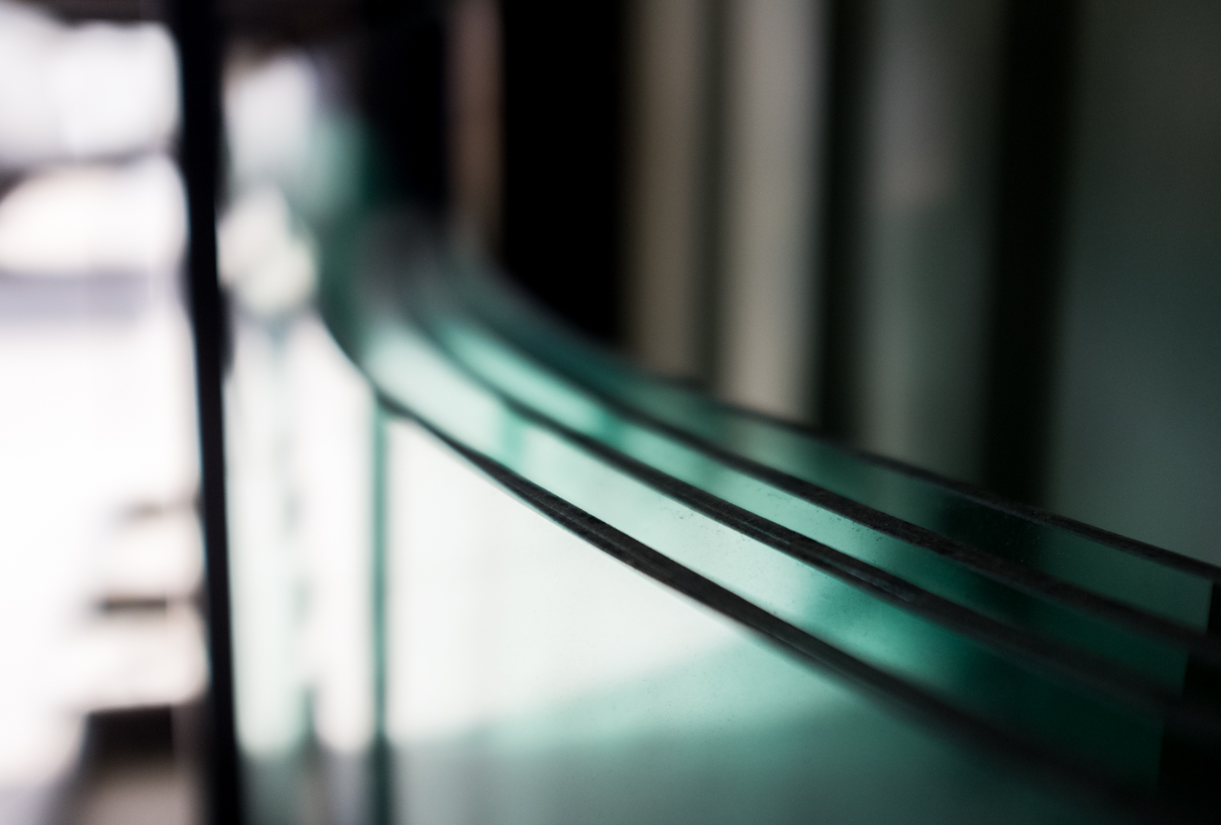 Close-up of curved, layered glass panels, possibly for a window or architectural element.
