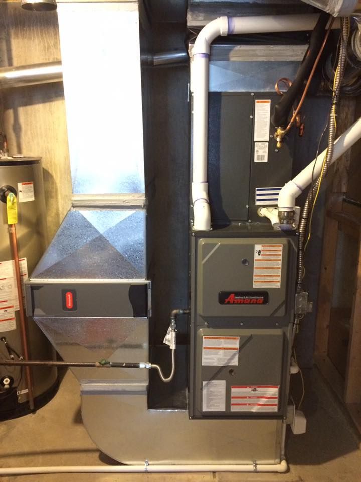Furnace and ductwork in basement, gray and silver with white pipes, next to hot water heater.