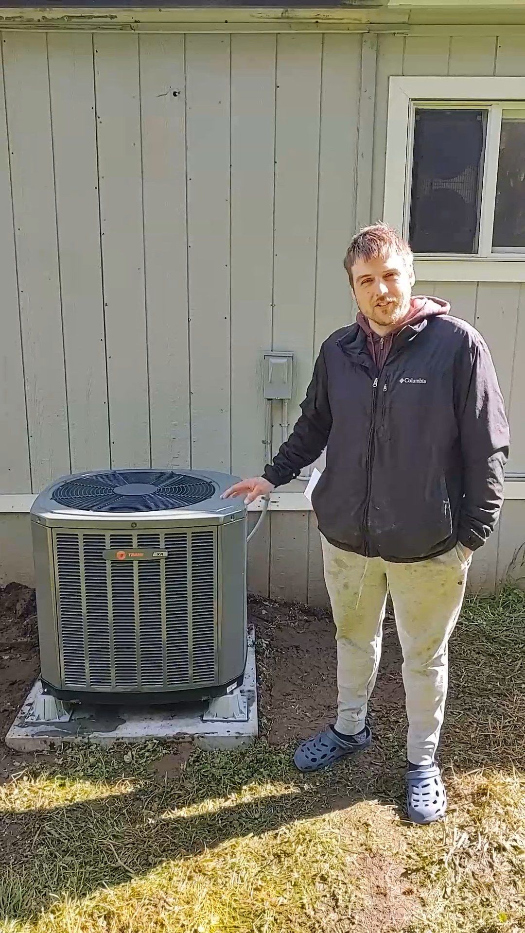 Man standing beside an air conditioner outside a building.