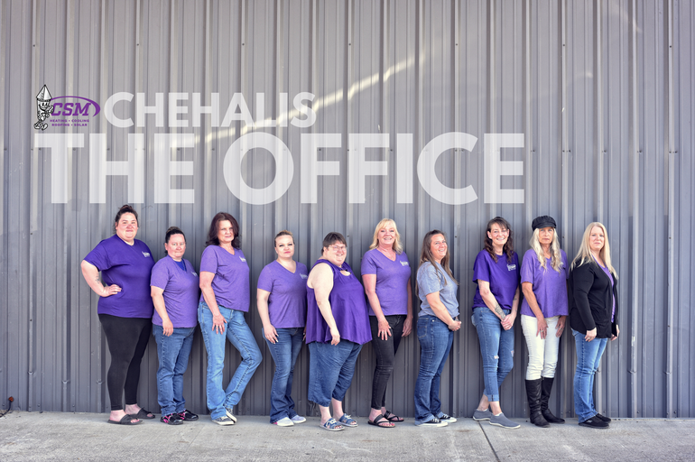 Group of eleven people in purple shirts and jeans in front of building with 