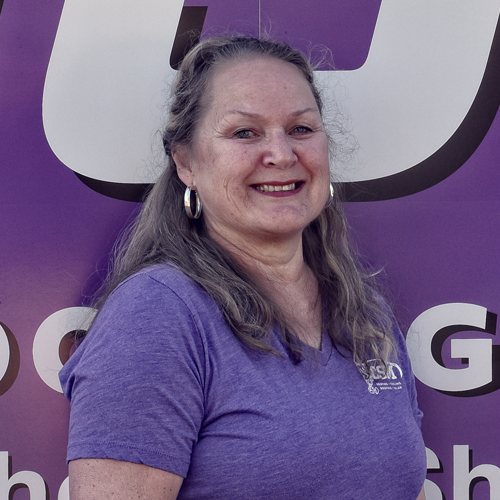 Woman in purple shirt smiles, standing in front of a purple background with text.