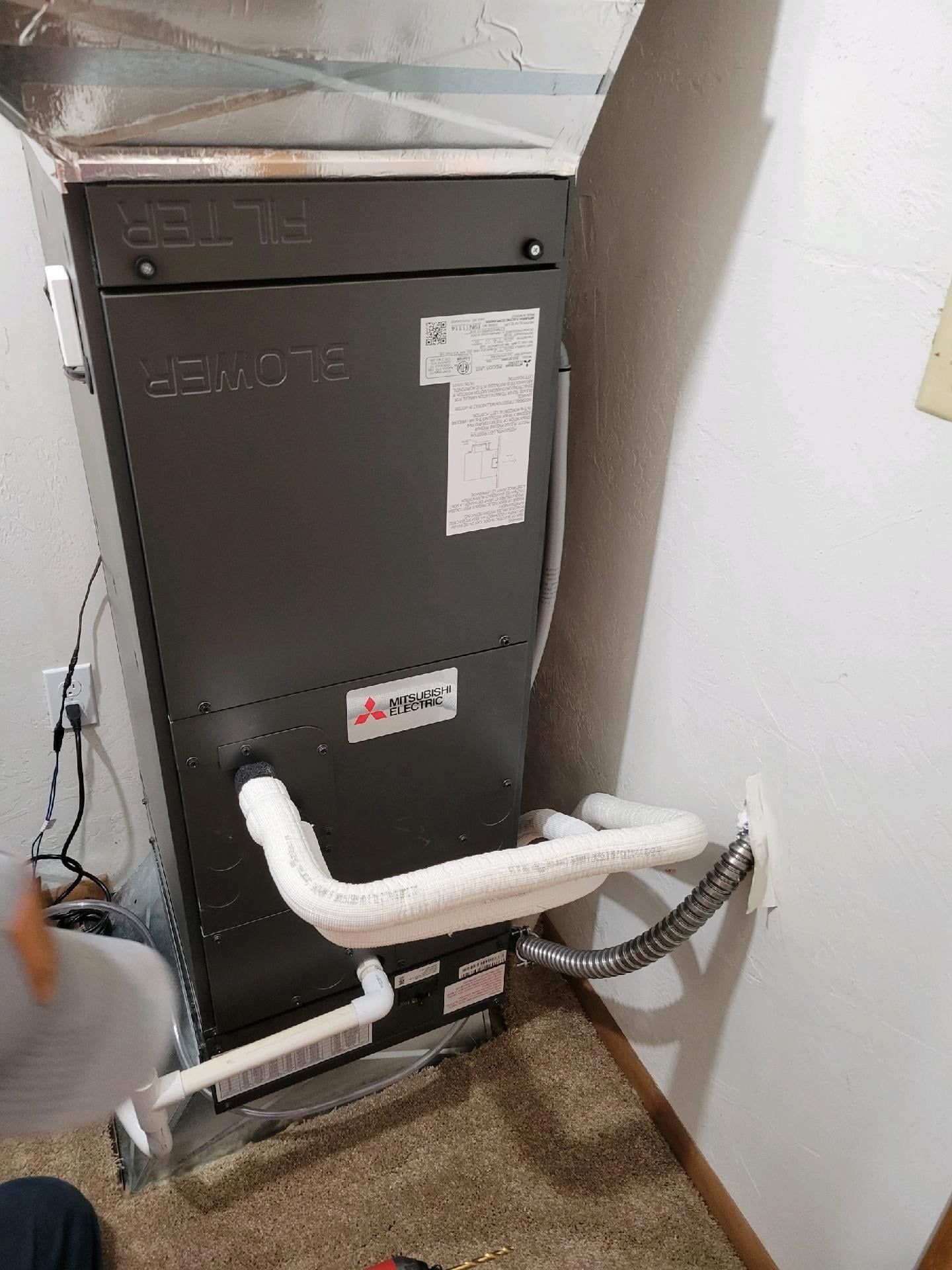 Lennox furnace unit with insulated refrigerant lines in a corner, installed near a wall outlet.