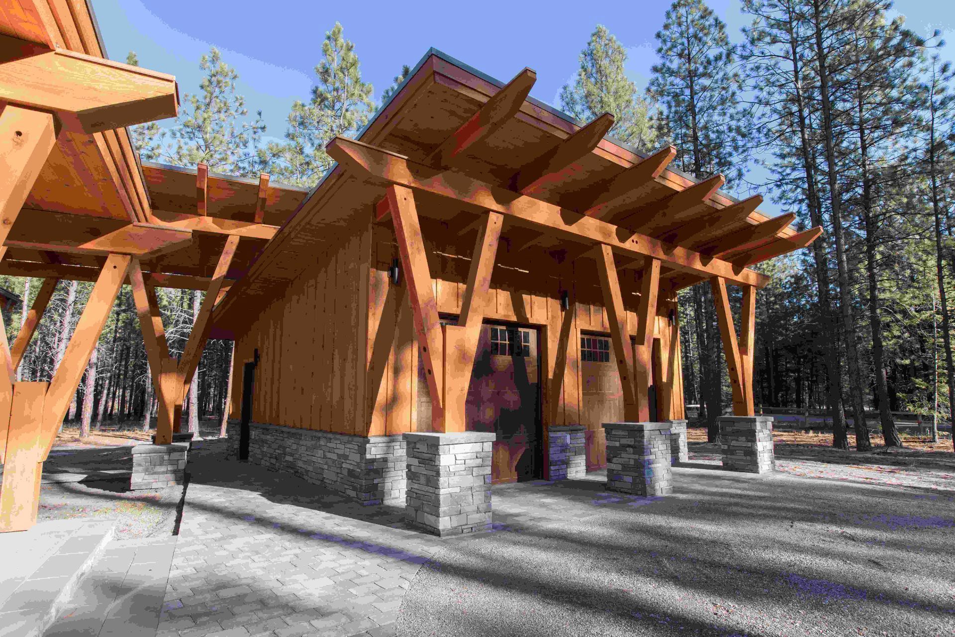 Modern wooden building with stone base among tall pine trees on a sunny day