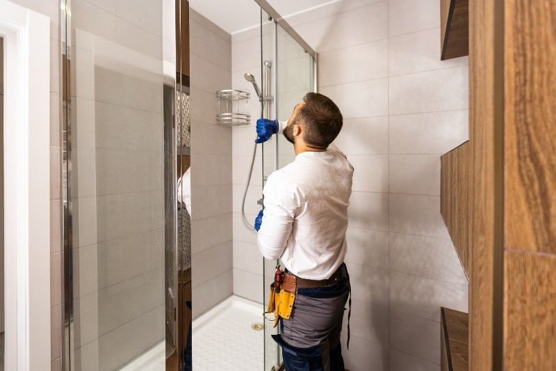 A man is installing a shower door in a bathroom.