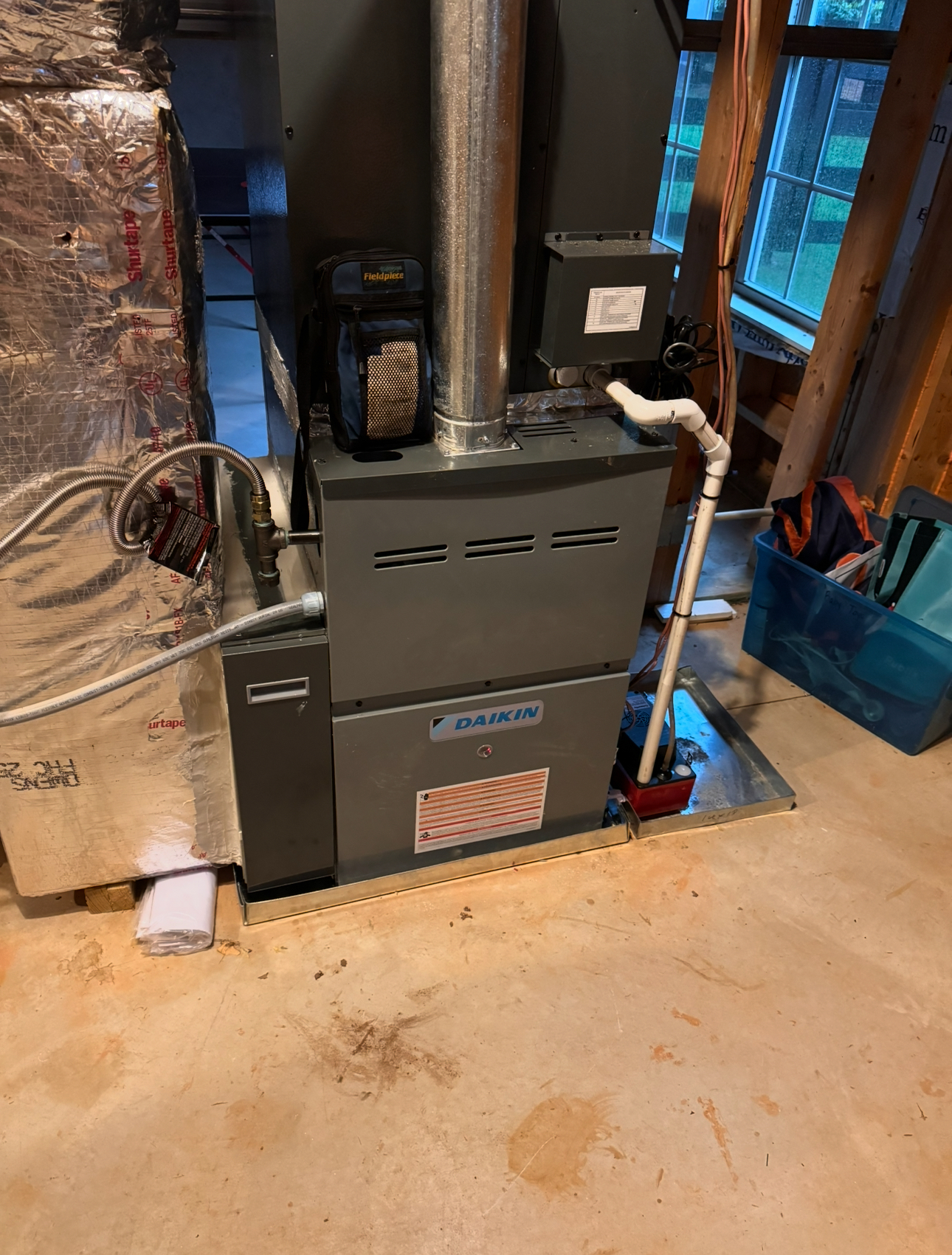 An outdoor heat pump unit next to a house wall and a pool in the background.