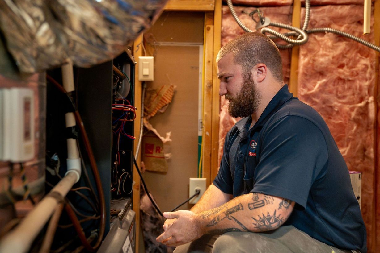 Technician working inside a wall cavity, inspecting wiring in a partially exposed room.