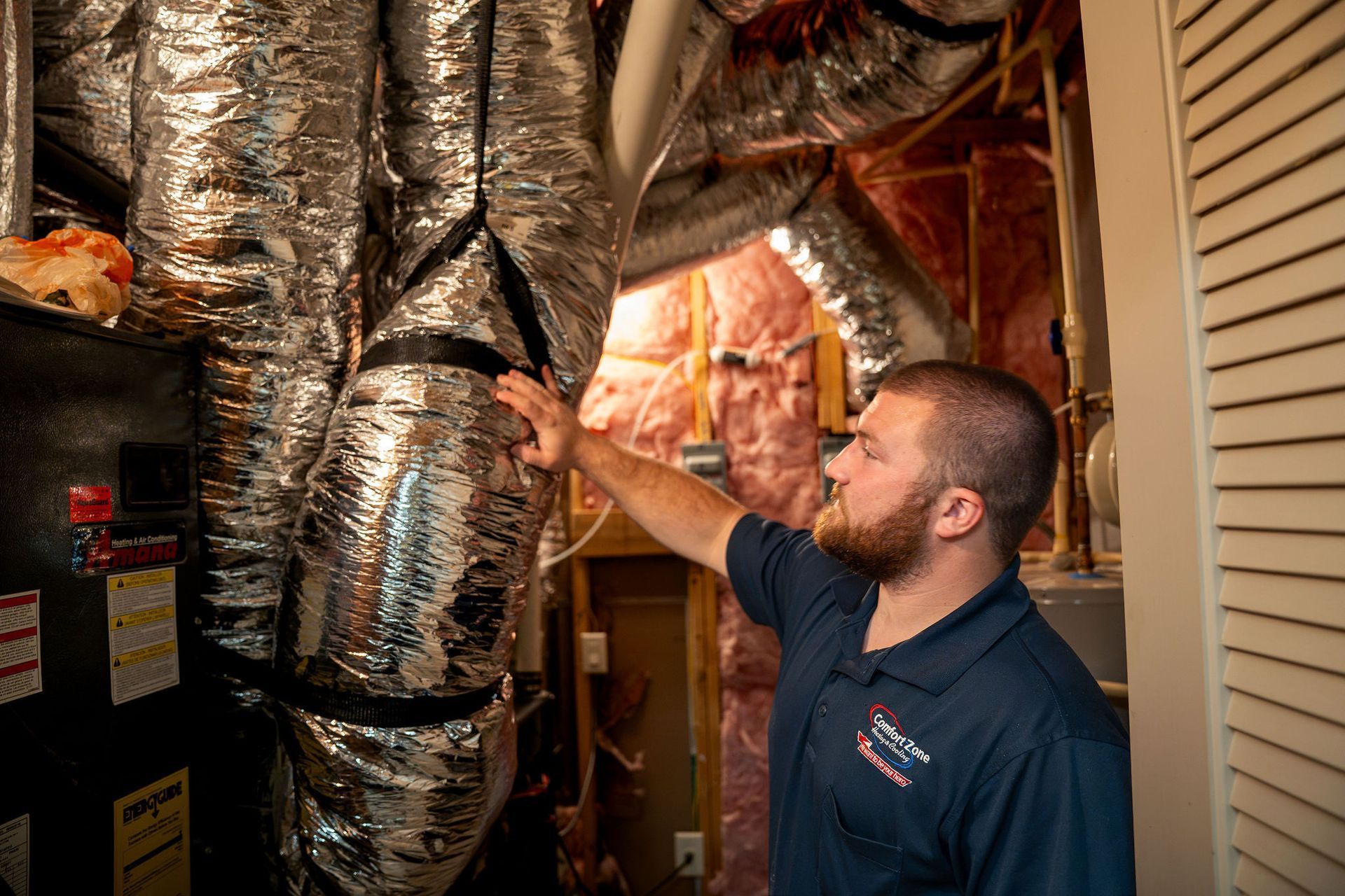 Technician inspecting insulated HVAC ducts in a home crawlspace