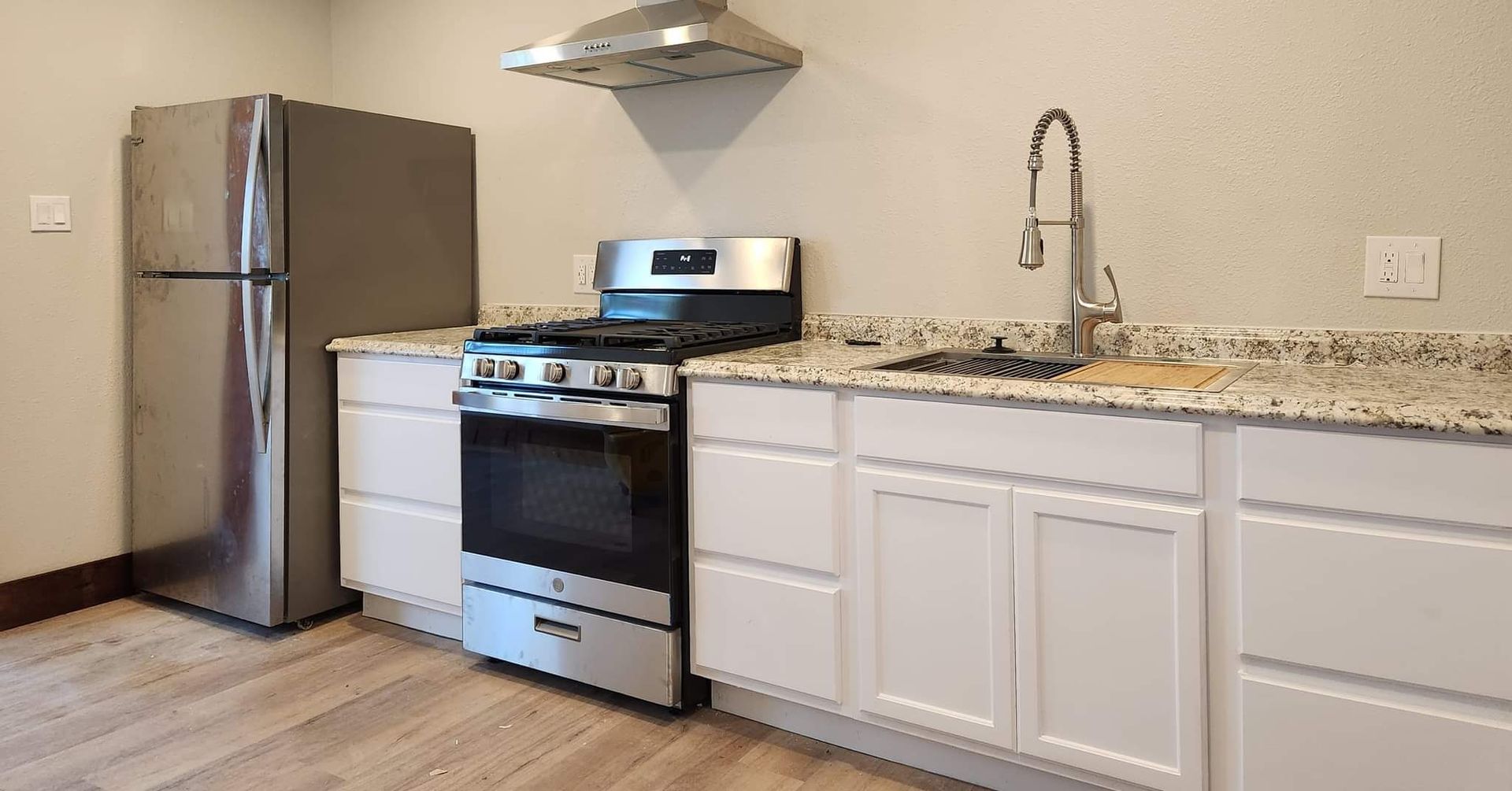 A kitchen with a stove, refrigerator, sink, and cabinets.