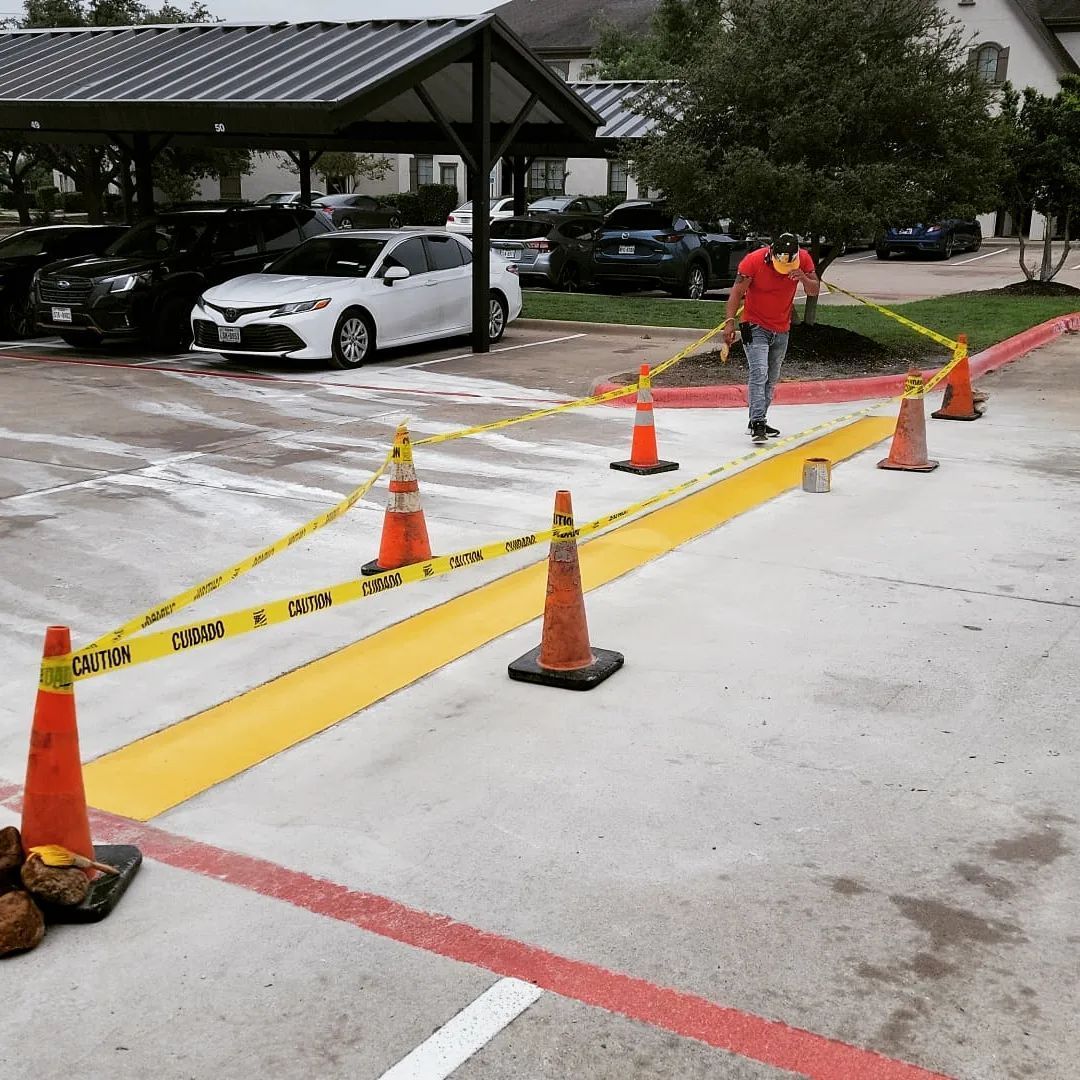 A man in a red shirt is walking across a parking lot with orange cones and yellow tape.
