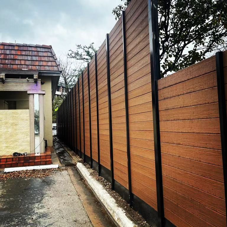 A wooden fence along a sidewalk in front of a building.