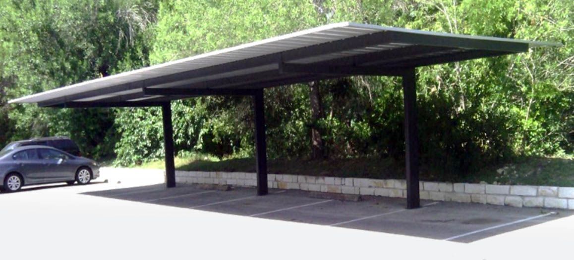 A car is parked under a canopy in a parking lot.
