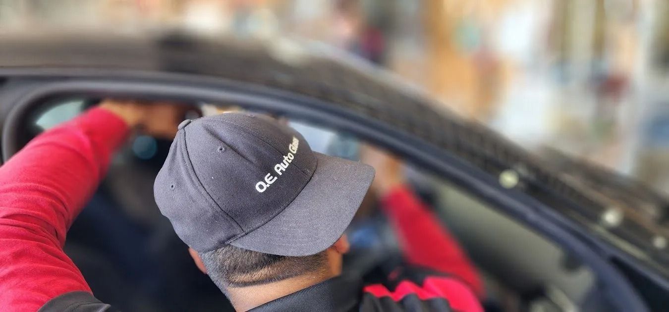 Person installing car window tint, wearing a hat that says 