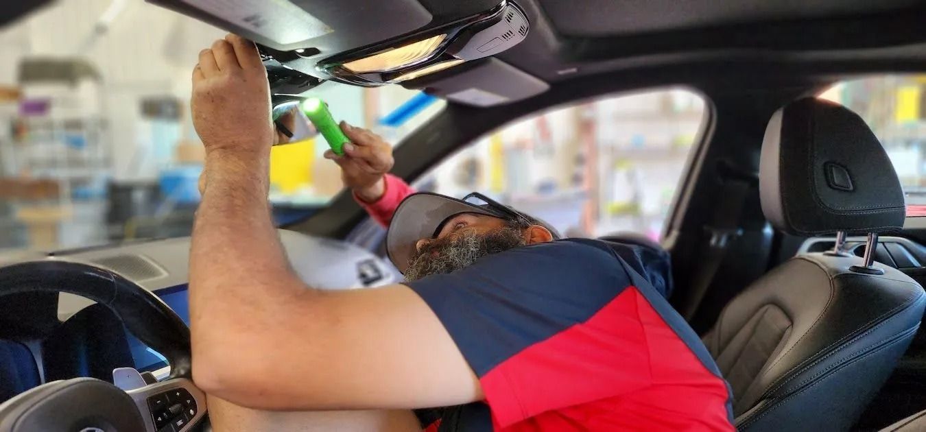 A person working on the interior of a car, using a flashlight.